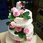 Tabler Hochzeitstorte mit feinen Rosen und süßem Brautpaar.